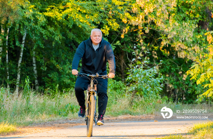 an elderly man rides a bike in the forest