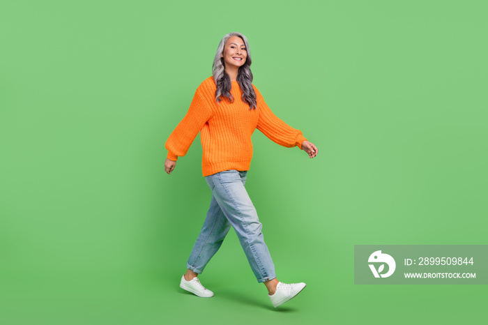 Full body photo of cute grey hair aged lady go wear pullover jeans sneakers isolated on green color background