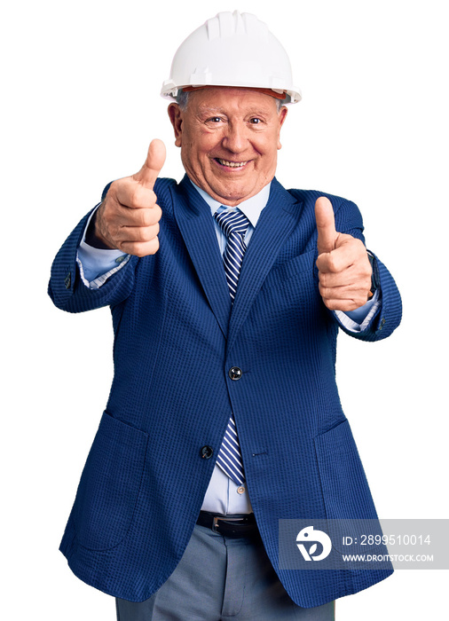 Senior handsome grey-haired man wearing suit and architect hardhat approving doing positive gesture with hand, thumbs up smiling and happy for success. winner gesture.