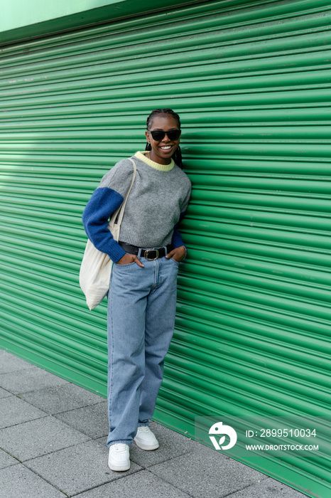 Young stylish woman standing in front of green door