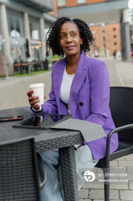 Thoughtful woman sitting with digital tablet during coffee break in cafe