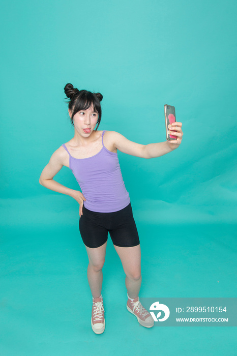 Studio shot of girl sticking out tongue and taking selfie