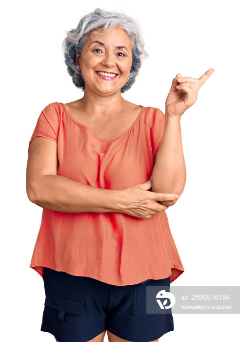 Senior woman with gray hair wearing orange tshirt smiling happy pointing with hand and finger to the side