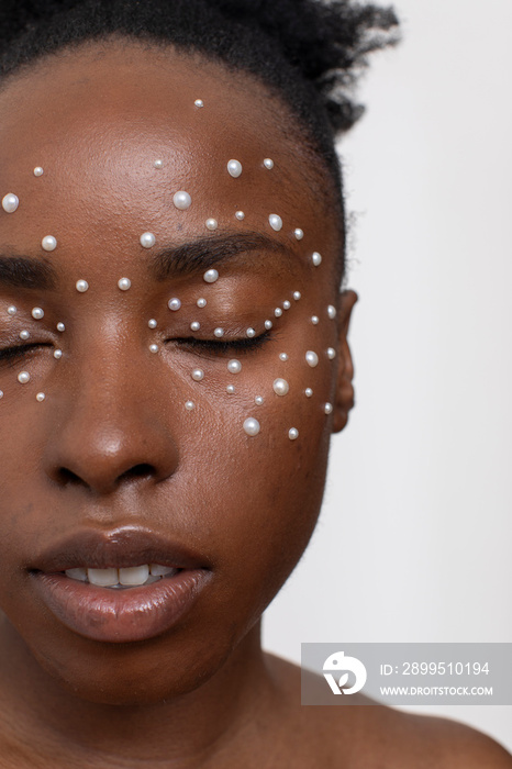 Young woman with closed eyes, wearing pearl freckles