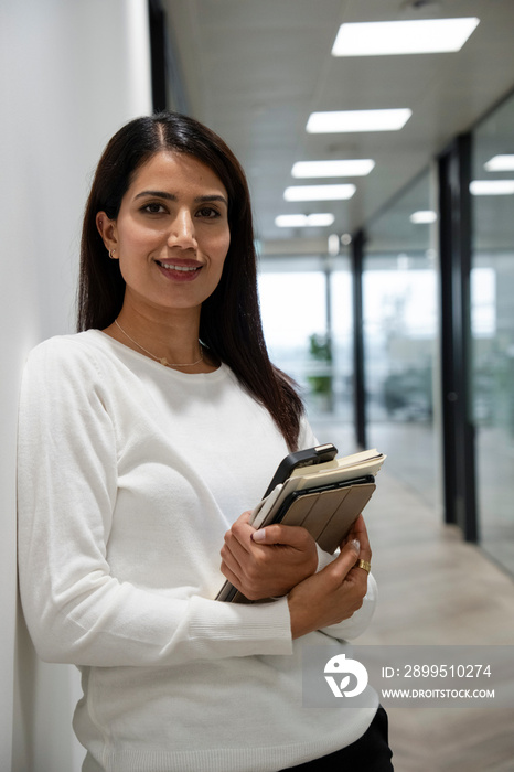 Portrait of businesswoman standing in office corridor