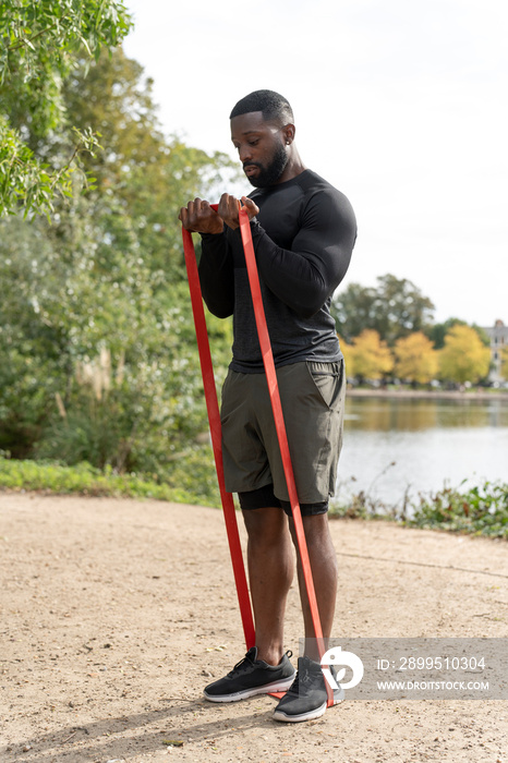 Athletic man exercising with resistance band in park