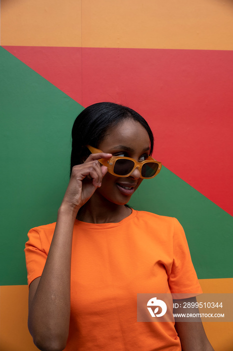 Smiling young woman in orange sunglasses