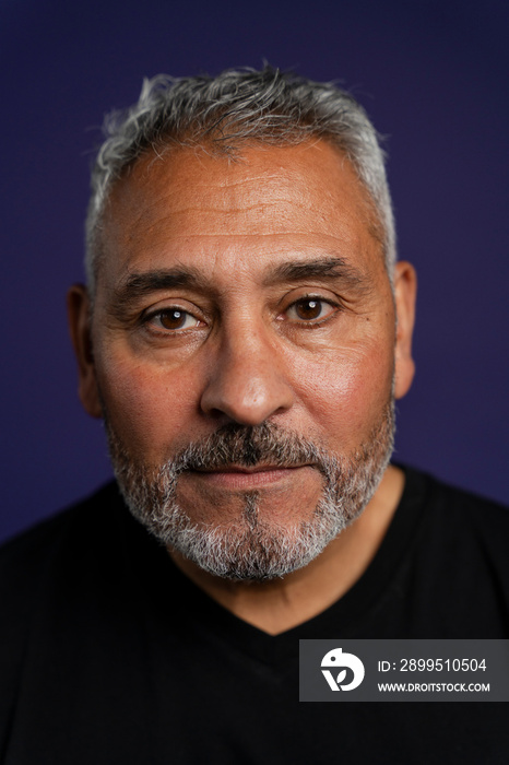 Portrait of serious man against purple background