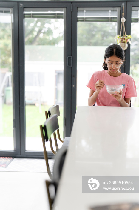 Girl eating breakfast at table in living room