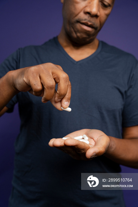 Man taking medicine against purple background