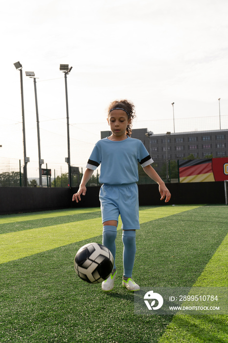 Girl (6-7) playing soccer on soccer field