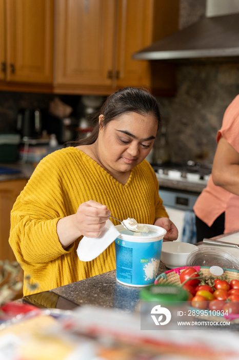 Young woman with down syndrome preparing food in kitchen