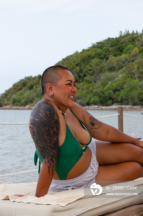 Cheerful woman relaxing on sun lounger near bay