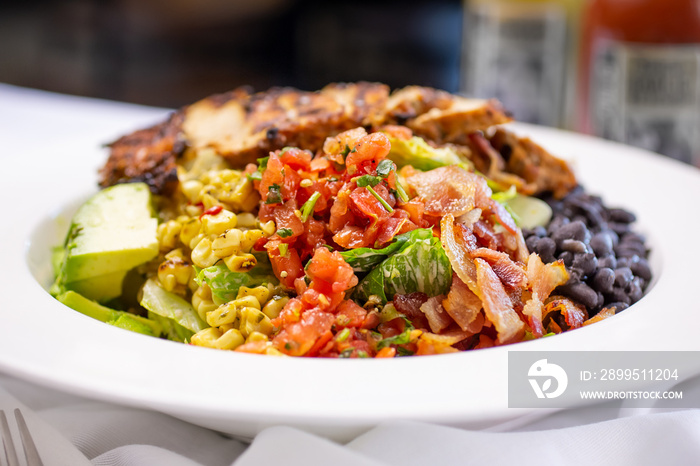 A closeup view of a Southwestern style mixed salad, in a restaurant or kitchen setting.