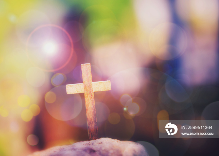 Close up of wooden cross on the rock over blurred colorful  Bokeh  light with word from bible verses, John 3:16 , Christian background with copy space.