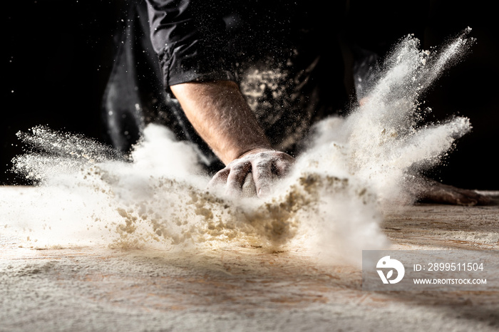 Photo of flour and men hands with flour splash. Cooking bread. Kneading the Dough. Isolated on dark background. Empty space for text