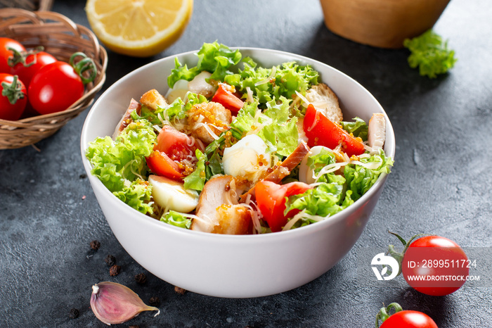 Caesar Salad with smoked chicken and parmesan on dark background. Copy space.