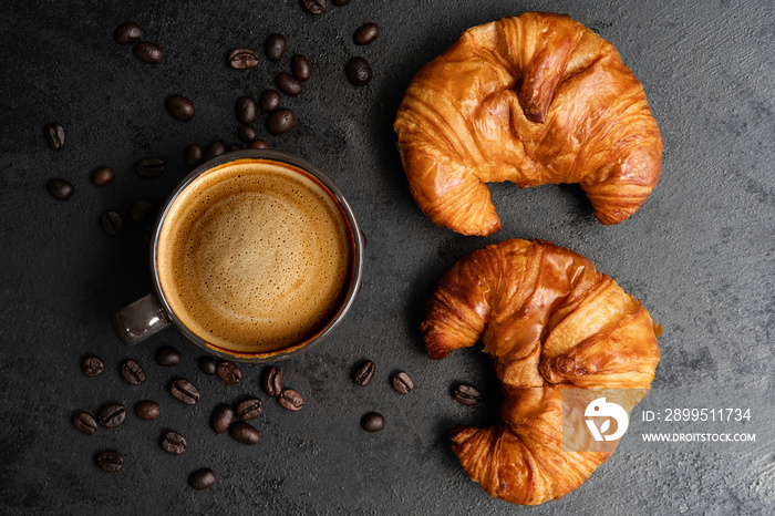 black coffee and fresh croissants on a dark background and bean