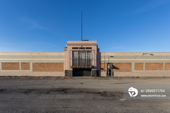 Exterior front of a long abandoned brick retail building with empty parking lot