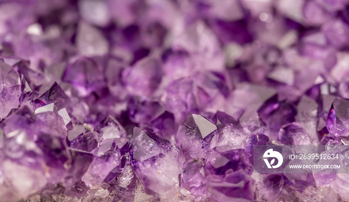 Amethyst purple crystals. Gems. Mineral crystals in the natural environment. Texture of precious and semiprecious stones. Seamless background with copy space colored shiny surface of precious stones.