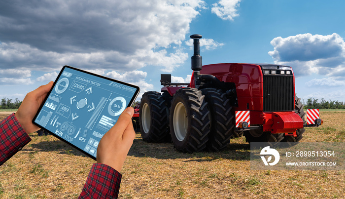 A farmer with digital tablet controls an autonomous tractor on a smart farm