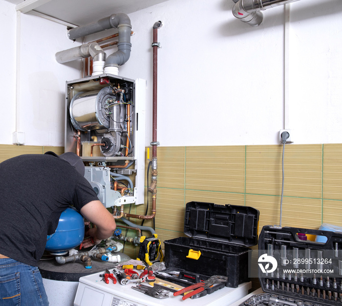 plumber fixing central heating system, Worker servicing a gas boiler