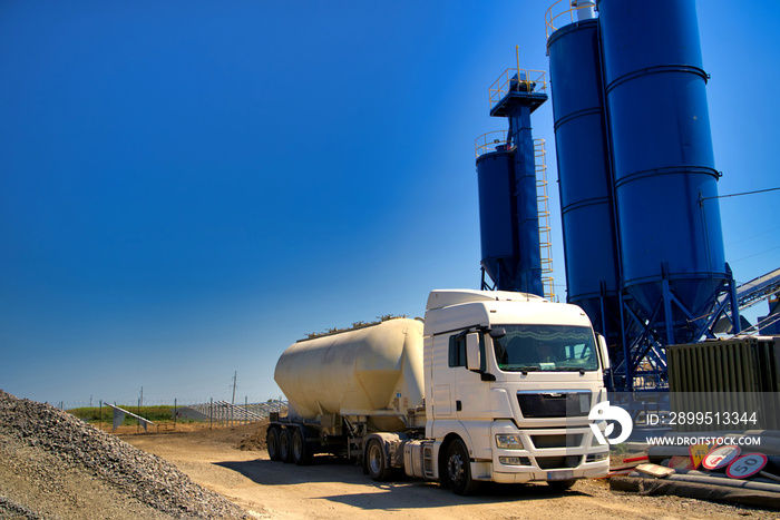 The truck near the concrete station. Asphalt production, Road construction. Blue sky background.