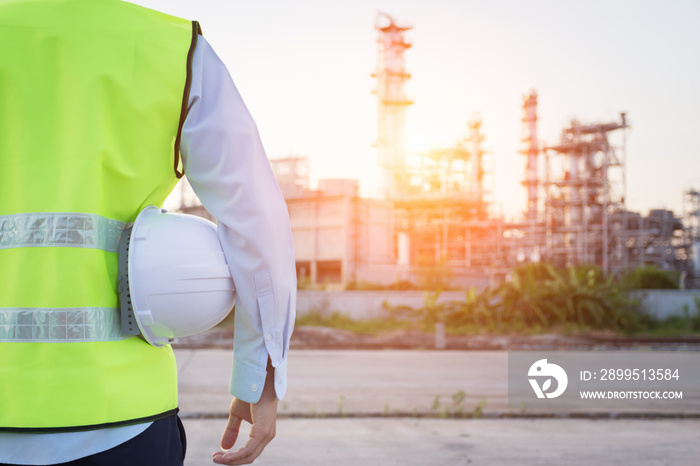 Engineering man standing with white safety helmet near to oil refinery