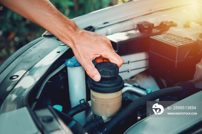 Man’s hand opening the power steering fluid tank cap