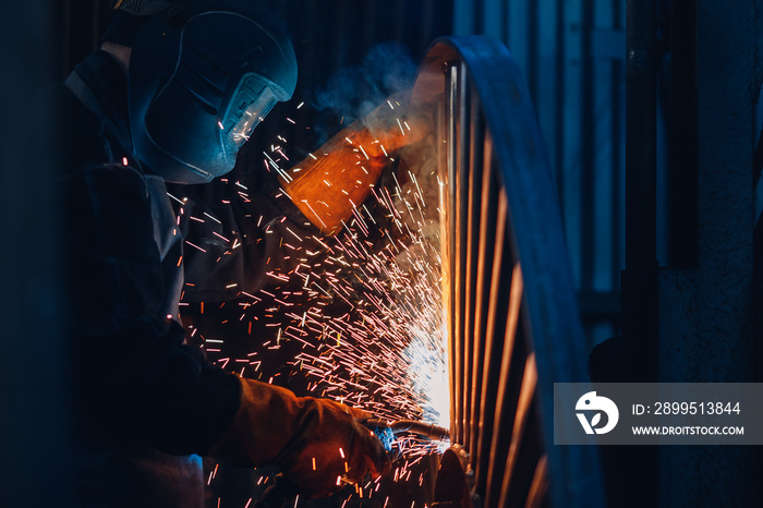 Industrial concept. Professional welder performs welding work on metal in protective mask