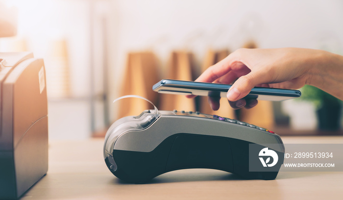 Customer using smartphone for payment by NFC technology on card reader machine.