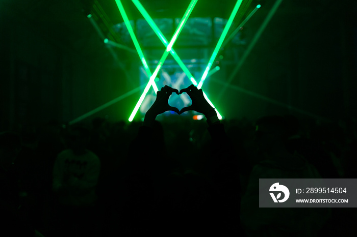 Woman showing heart symbol in the crowd on a party