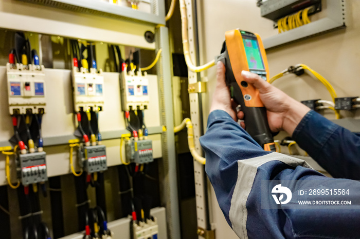 Electrician inspects the power control to find the abnormal condition of transformer by using thermo scanner.