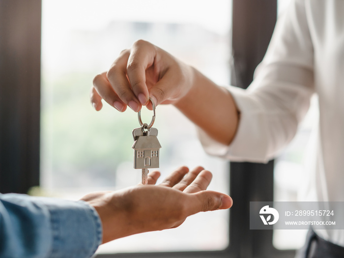 Realtor agent giving a key of apartment to new owner after signed lease agreement.