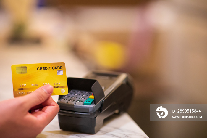 close up of hand holding credit card with EDC (Electronic Data Capture) machine