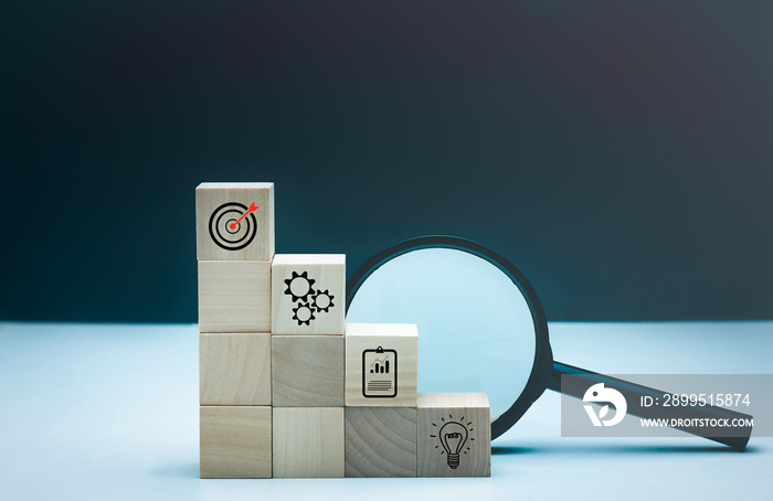 Plan and strategy business icon on wood cubes, magnifying glass for business concept