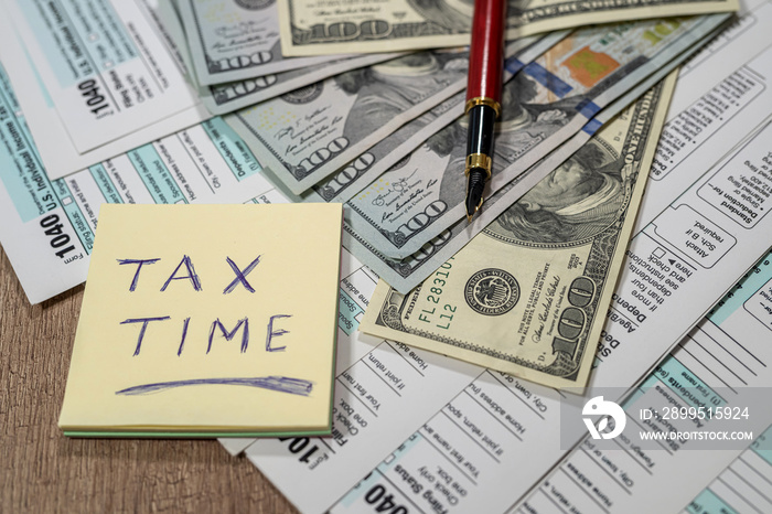 tax form 1040 with dollars, pen and calculator on a table made of beautiful wood.