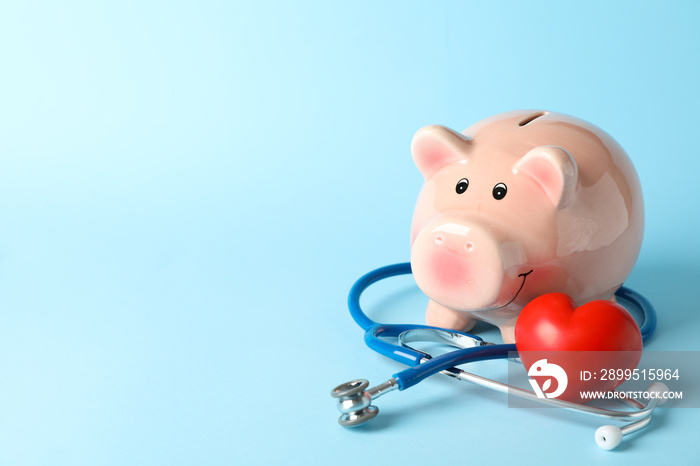 Stethoscope and piggy bank on blue background, space for text