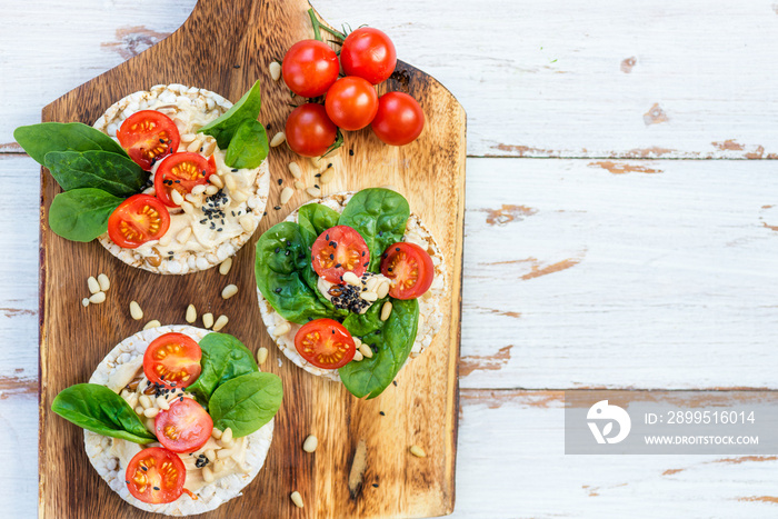 Healthy Snack from Rice Cakes with Hummus, Spinach and Tomatoes