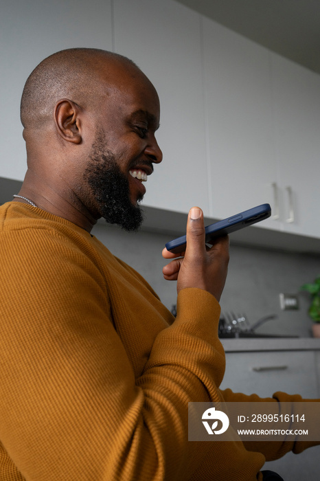 Smiling man using smart phone in kitchen