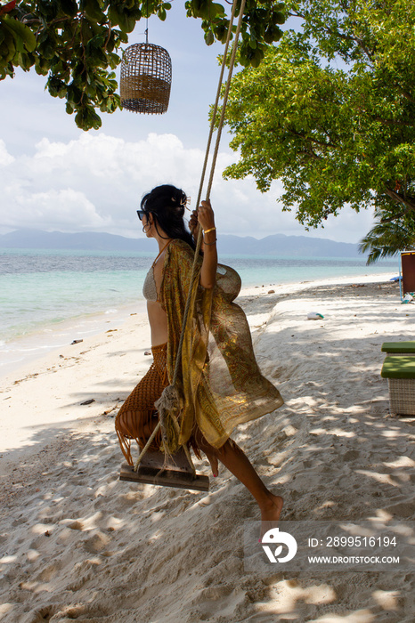 Mature woman swinging on swing on beach