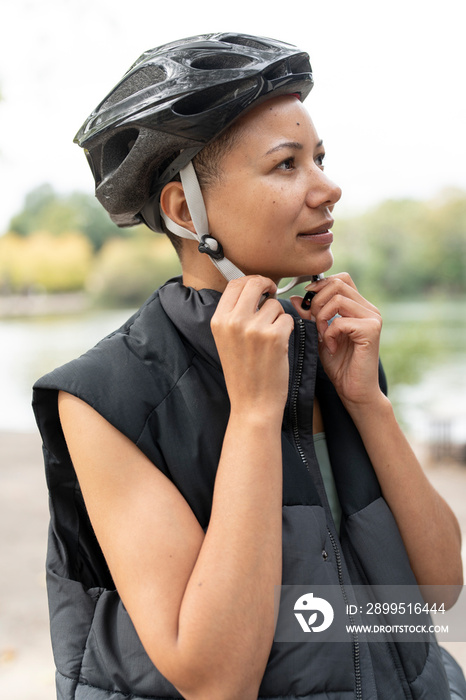 Woman fastening bike helmet in park