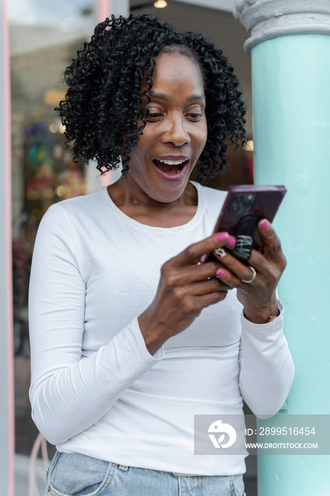 Smiling woman using smart phone in front of building