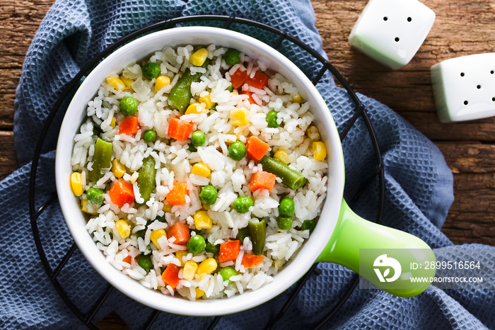 Cooked white rice mixed with colorful vegetables (onion, carrot, green peas, corn, green beans) in bowl, photographed overhead