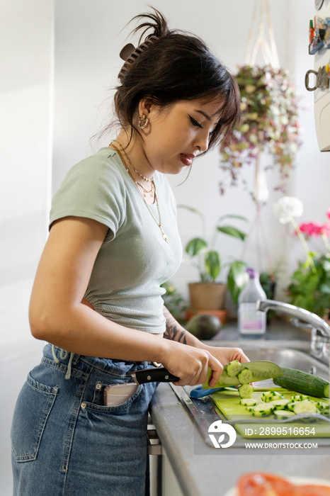 Young woman chopping vegetables in kitchen