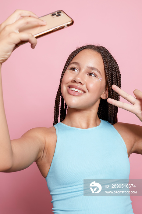 Studio shot of smiling girl with braids taking selfie