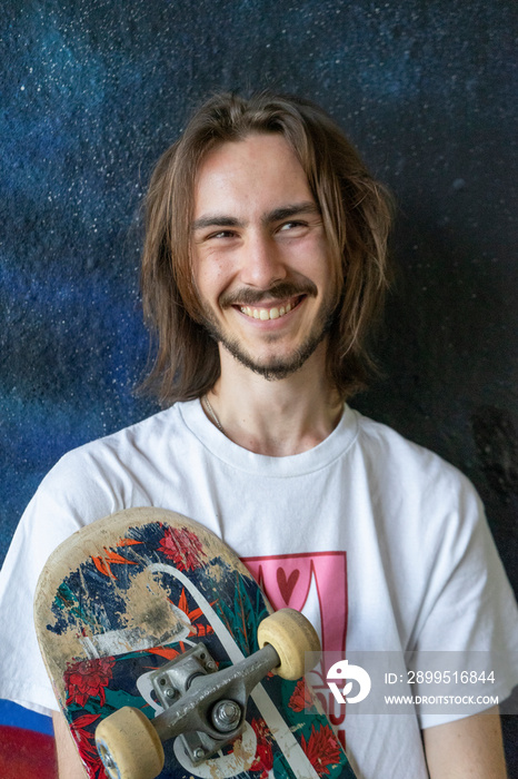 Young man holding skateboard and smiling