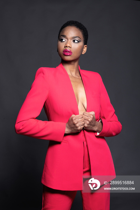 African young woman in red suit posing on black background.