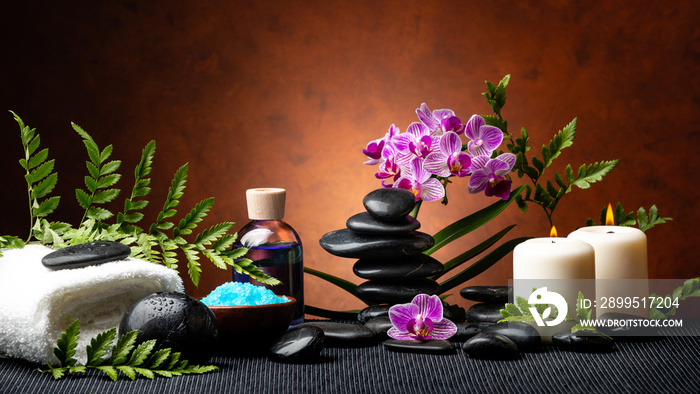 candle light spa treatment set with aromatic salt, perfumed essence, stones and orchid flowers with ornamental fern