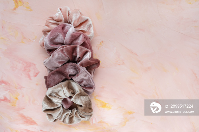 Collection of trendy velvet scrunchies on pink background. Diy accessories and hairstyles concept, copy space